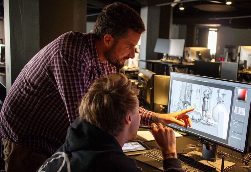 Image of 2 men huddled around a screen doing 3D modelling work 