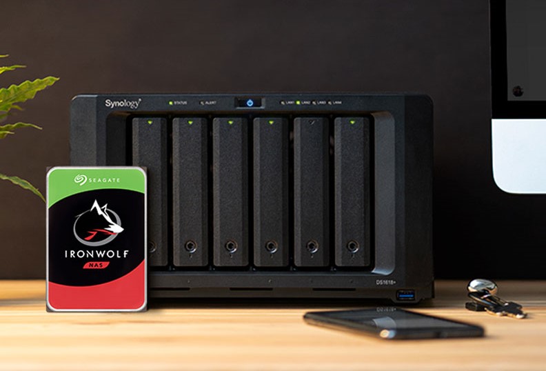 Image of a Seagate Iron Wolf NAS drive in front of 6-drive NAS enclosure sat on a desk
