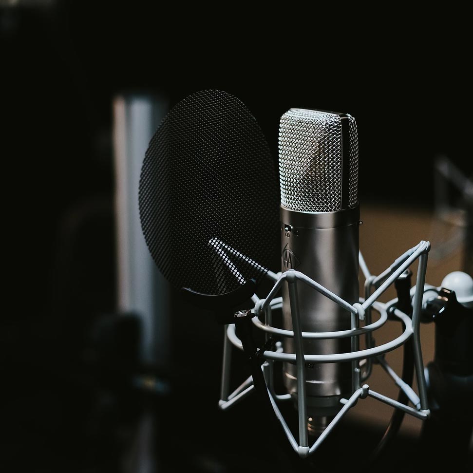 Image of a microphone with a pop filter attached to a microphone arm 